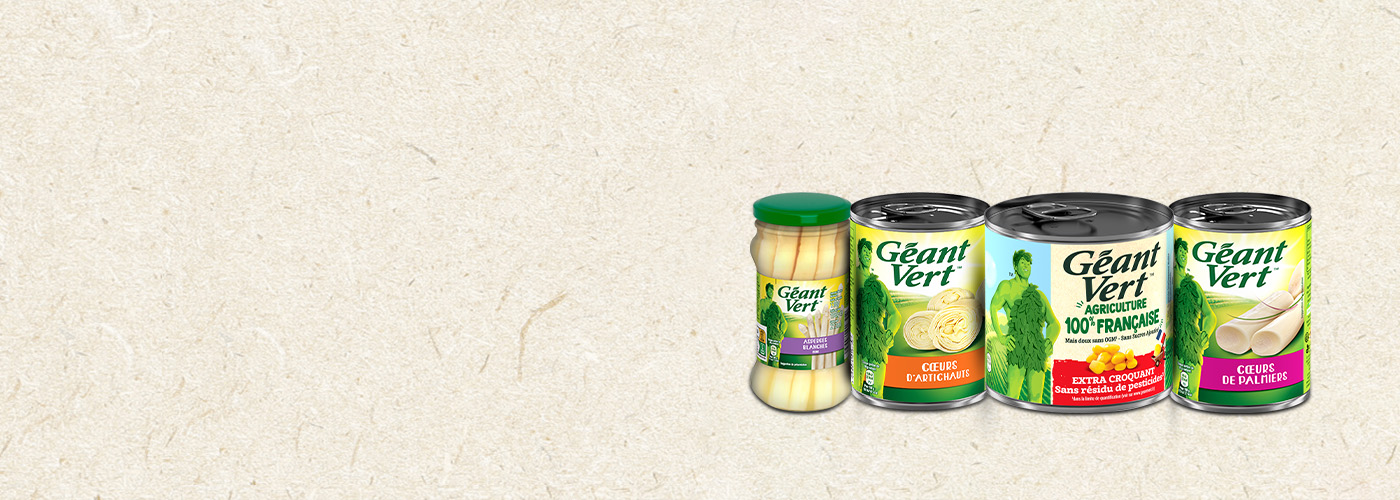 Géant Vert product range featuring a jar of white asparagus and cans of artichoke hearts, sweet corn, and palm hearts displayed on a beige textured background.